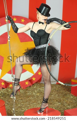 Circus performer in a black top hat standing on a pedestal and holds a rope ladder