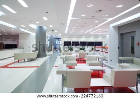 Empty waiting area with white chairs and plasma screens in a modern office
