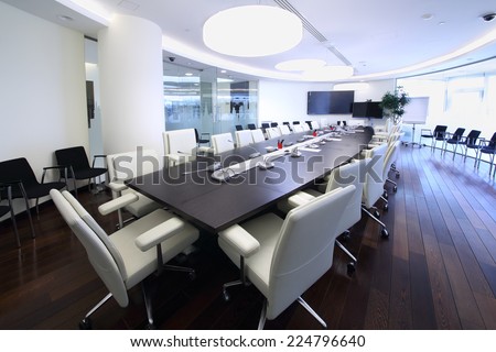 Bright and spacious conference hall with long negotiating table and white chairs in office