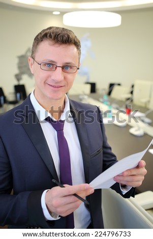 Portrait of happy businessman with a sheet of paper in his hands in office
