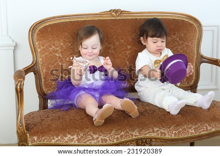 Beautiful little children in white and purple costumes sitting on couch
