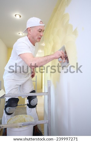 Plasterer applied with a trowel yellow decorative plaster on the wall