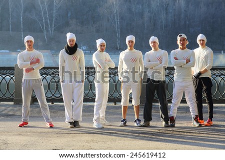 Group of seven young men in white shirts and hats stand in line on waterfront