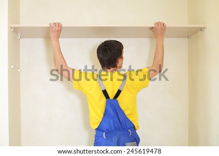 Worker fixes a shelf in the wall for the sliding wardrobe
