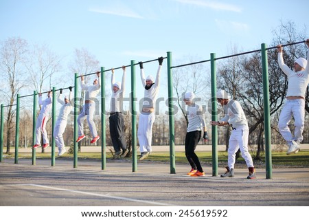 Eight young people hang on the horizontal bar on the playground