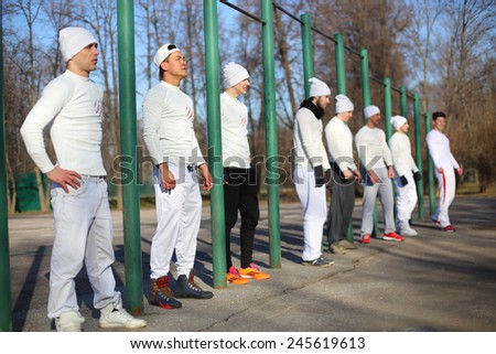 Eight young men near the long horizontal bar at the playground