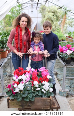 Mother with daughter and son driven cart with beauty flower in the greenhouse