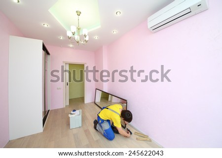 Worker setting mirror door for sliding wardrobe in room with pink walls