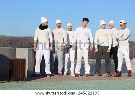 Group of seven young handsome men in white shirts and hats stand in line on waterfront
