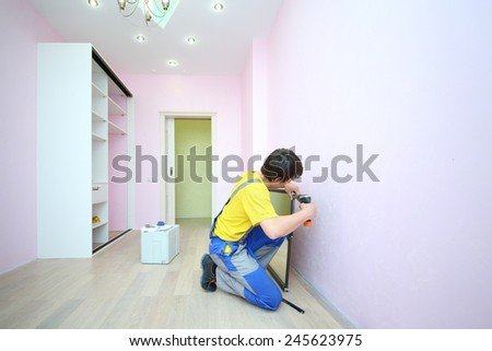 Man installing mirror door for sliding wardrobe in room with pink walls