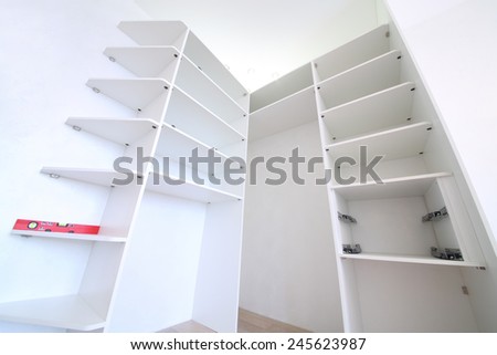 Installation of white corner sliding wardrobe without doors with shelves and red level