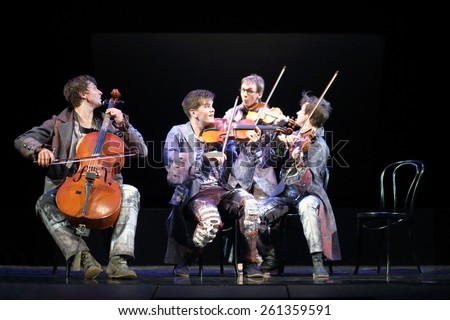 MOSCOW - MAR 12, 2014: Four funny men Taper-show: dancing on the strings in costumes with musical instruments sitting on chairs on stage of the Palace on Yauza