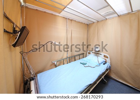 Simple interior hospital room with a bed, a TV and electroencephalograph