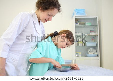 Girl and medical worker looking at the contents of a metal bowl in the exam room
