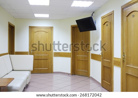 Interior of waiting area with five doors and a white sofa in the medical center hospitals