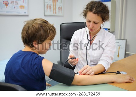 Health worker measures the pressure of the boy in exam room