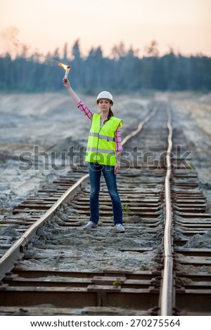 female worker lights signal torch on rails