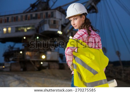 female worker standing with scheme on rails on backgroud of career stacker