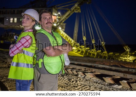 two workers stand back to back  on background of career stacker