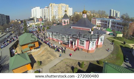 MOSCOW, RUSSIA - APRIL 19, 2014: Many people stand at long table near Sunday school in Church of Transfiguration Savior in Bogorodskoe during Holy Saturday before Easter, aerial view
