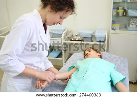 Health worker measures the pulse of a little girl in exam room