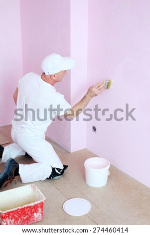Man in white clothes covers the walls pink decorative plaster
