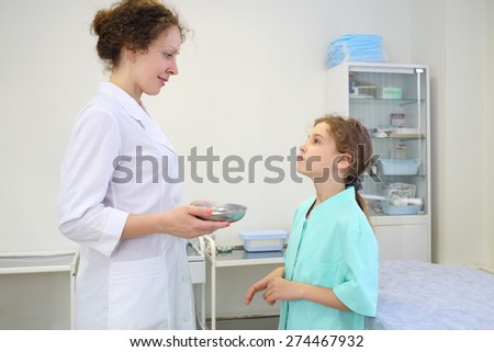 Girl in hospital gown looking at the doctor in the room