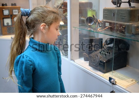 MOSCOW - APR 05, 2014: Girl examines vintage telephone exhibits in the Museum of the History telephone in Moscow