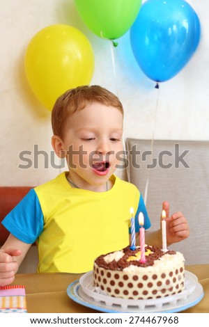 Little boy blows out the candles on the birthday cake in cafe