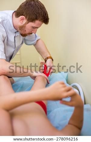 red-haired physician puts fixing tape on the child feet