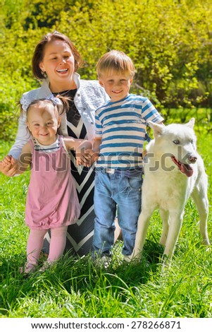Mom with her daughter and son sitting with dog on grass in park