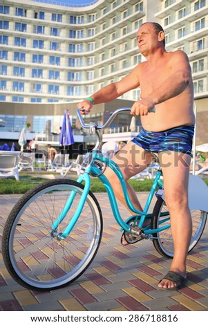 Elderly man in bathing suits on bikes on the hotel in the evening