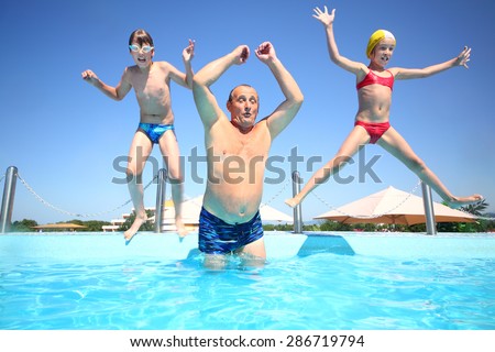 Grandfather with boy and girl jumping into a pool of water