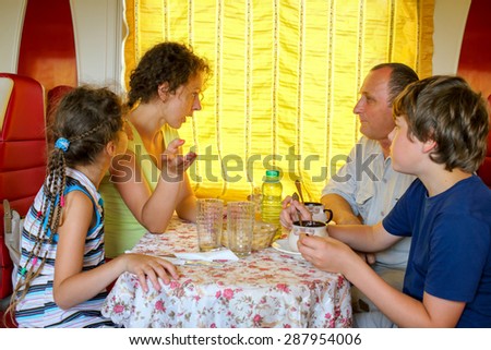 family of four talking  at a table in the dining car of the train