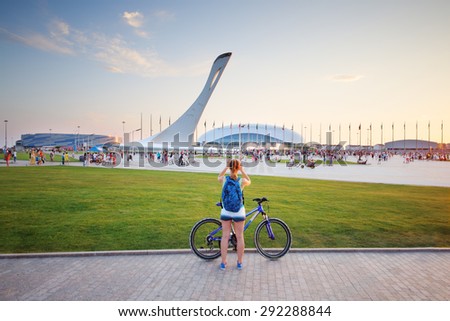 SOCHI, RUSSIA - JUL 27, 2014: Tourists walk in the Olympic park with a bowl of the Olympic flame and the stadium Fischt