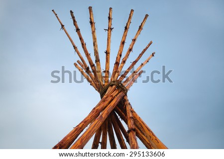 Tipi on blue sky background (Tipi - structure in shape of cone, which is based on multiple poles).