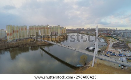 MOSCOW - APR 24, 2015: Many people walk by pedestrian bridge at spring cloudy day. Aerial view