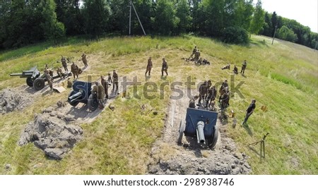 RUSSIA, MOSCOW - JUL 12, 2014: Soldiers in uniform of Soviet Army of World War II stand near three guns on battle field at spring sunny day. Aerial view. Photo with noise from action camera.