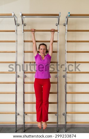 woman hanging on a horizontal bar in a gym