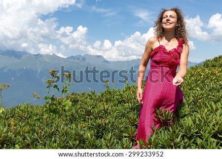 woman in evening dress gathering berries in the mountains