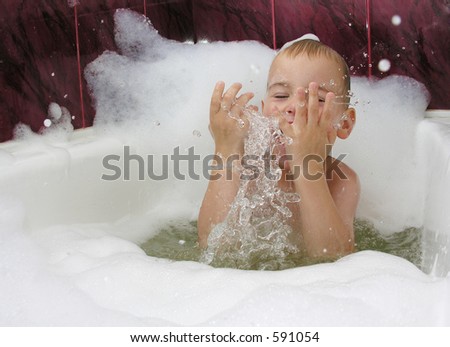 boy in bath with splash of water in hands