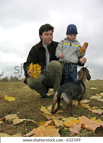 father with son and dog on autumn leaves