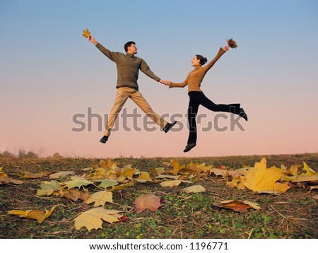 jump couple. autumn leaves. sunset sky