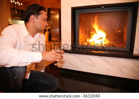 man and fireplace, focus on glass - stock photo