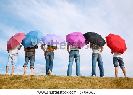 the group of people stands with the umbrellas on to meadow by the back