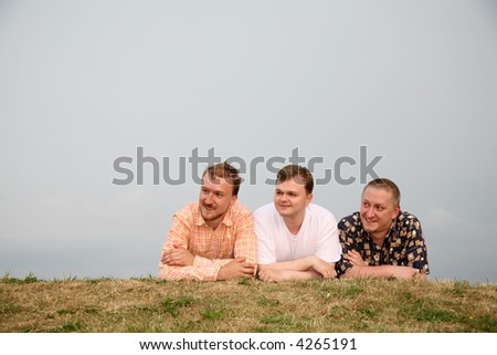 three men, laying on the grass