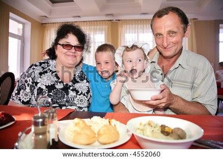 Grandmother with grandfather behind table with grandson and granddaughter