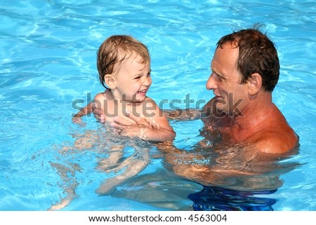 Grandfather and grandchild playing together in the pool. Outdoor, summer.