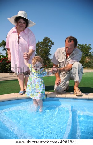 Grandfather, grandmother hold granddaughter in pool