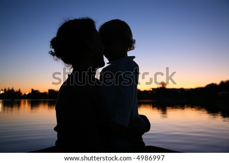 the silhouette of mother with the child against the background of the sunset